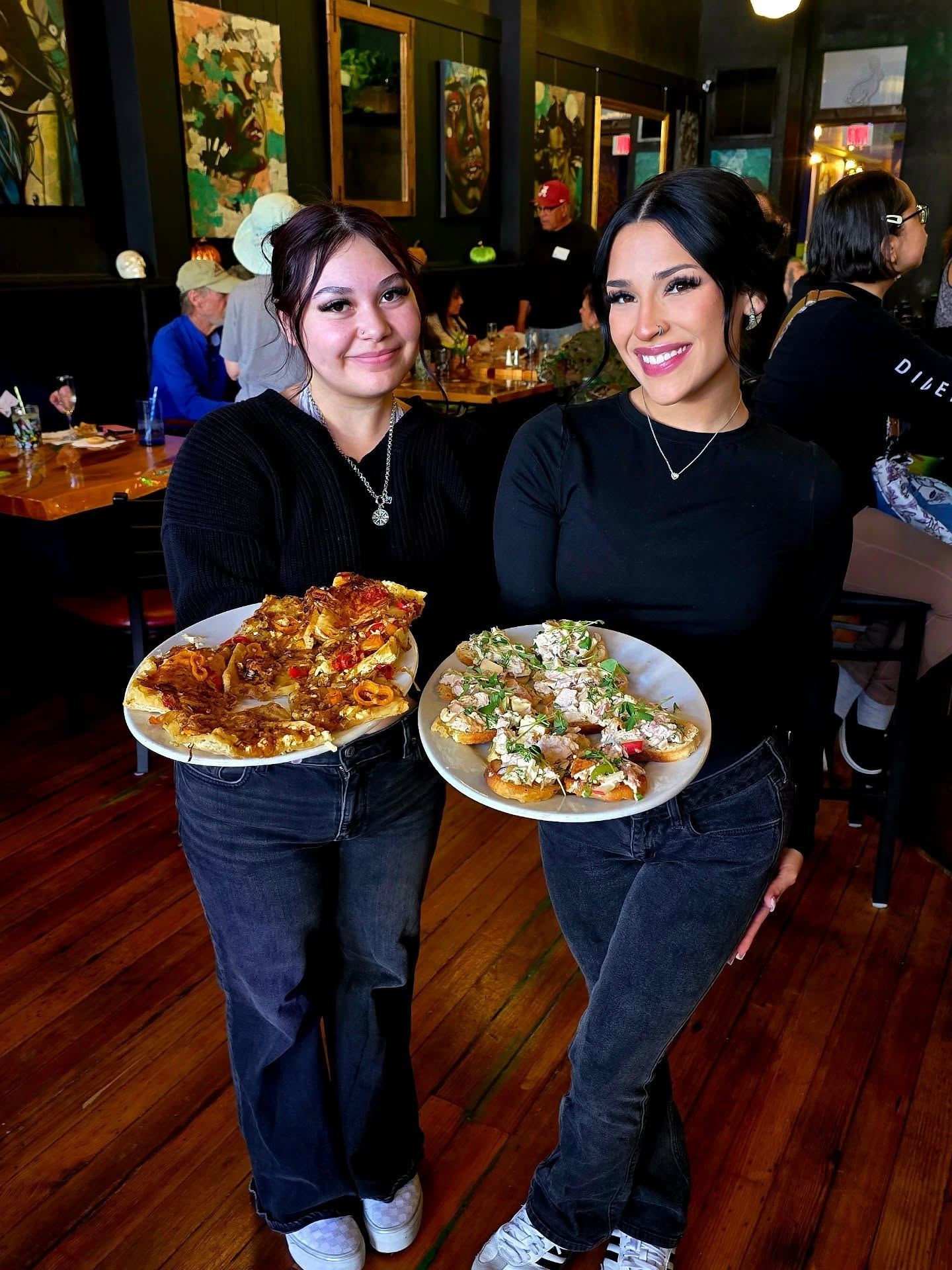 Two Borracho's servers holding plates of flatbread pizza and chicken salad crostini